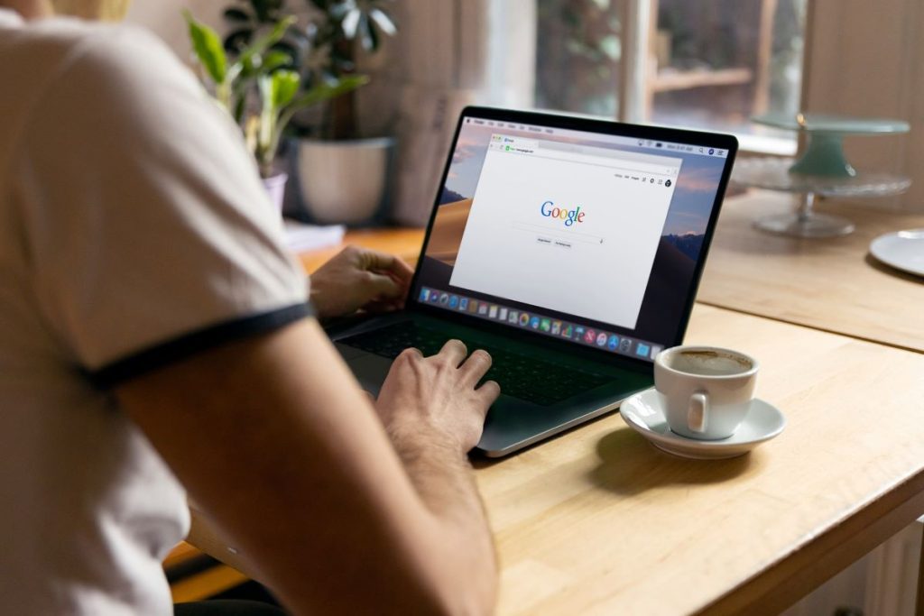 Person-sitting-on-a-table-using-his-laptop