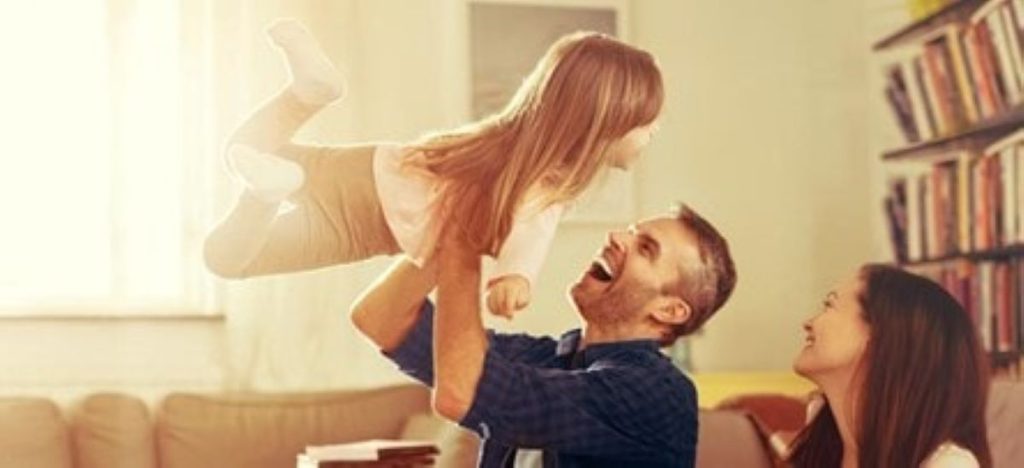 Photo of a family playing with the father carrying the daughter