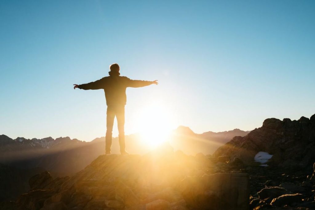 photo of a man standing before the sun rise