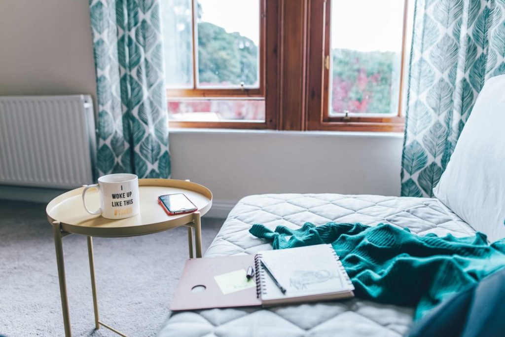 photo of a bed and a bedside table with a mug of coffee