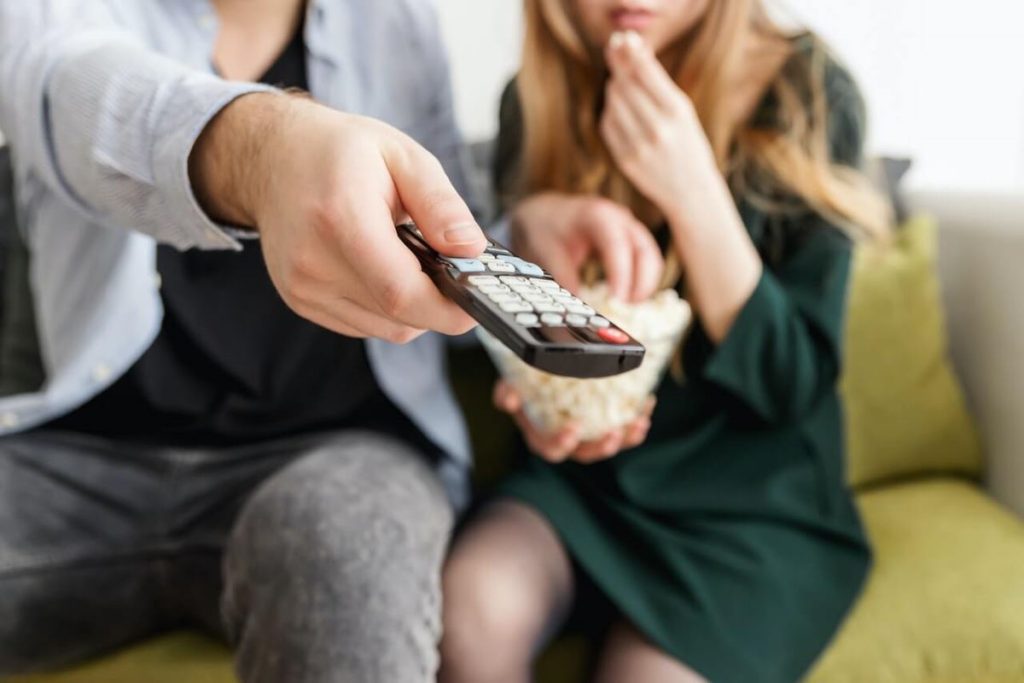 photo of a couple holding a remote to watch a movie