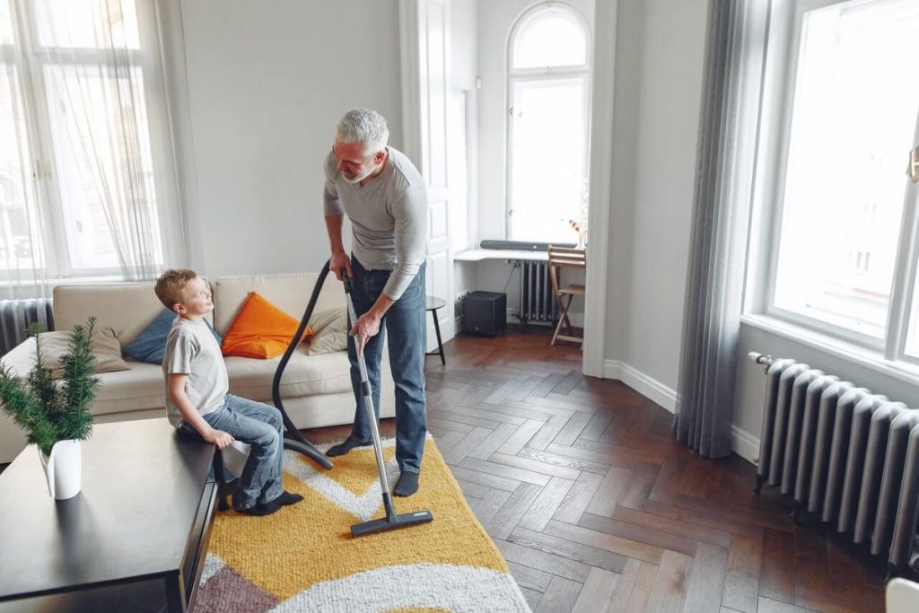photo of a father and son vaccuuming a carpet