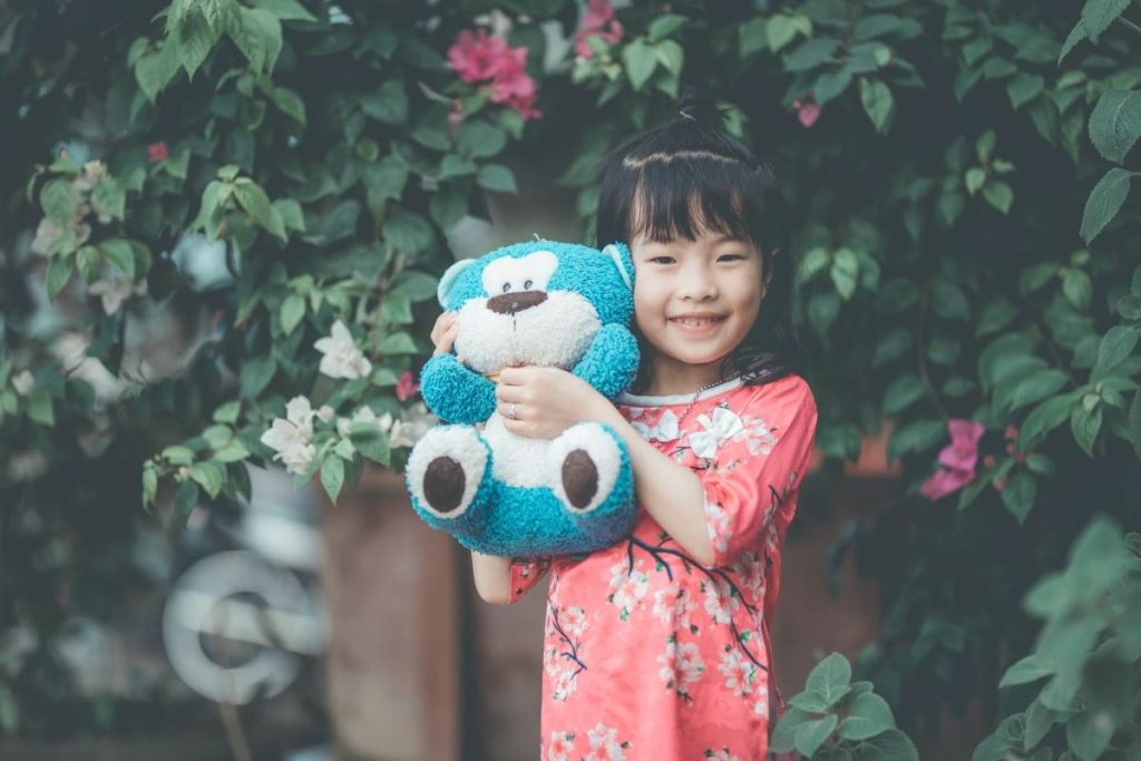 photo of a girl holding blue stuffed toy