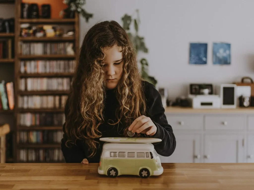 photo of a girl putting money in her piggybank