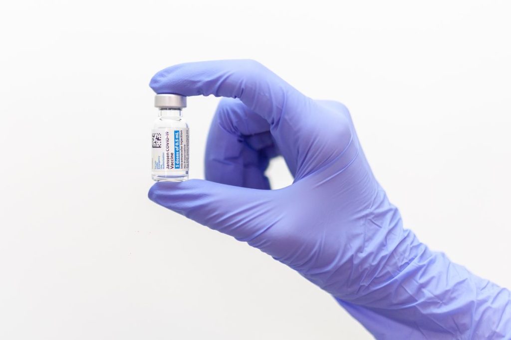 photo of a gloved hand holding a vial of the vaccine
