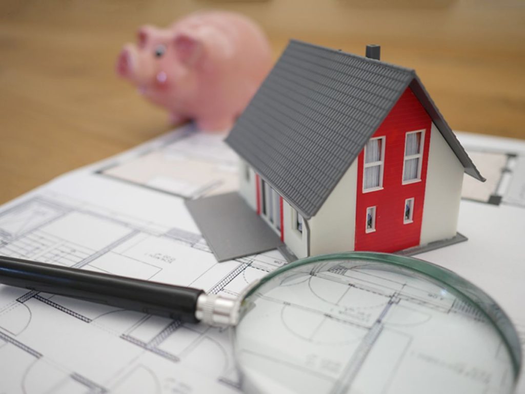 photo of a house diagram on blueprints and a magnifying glass