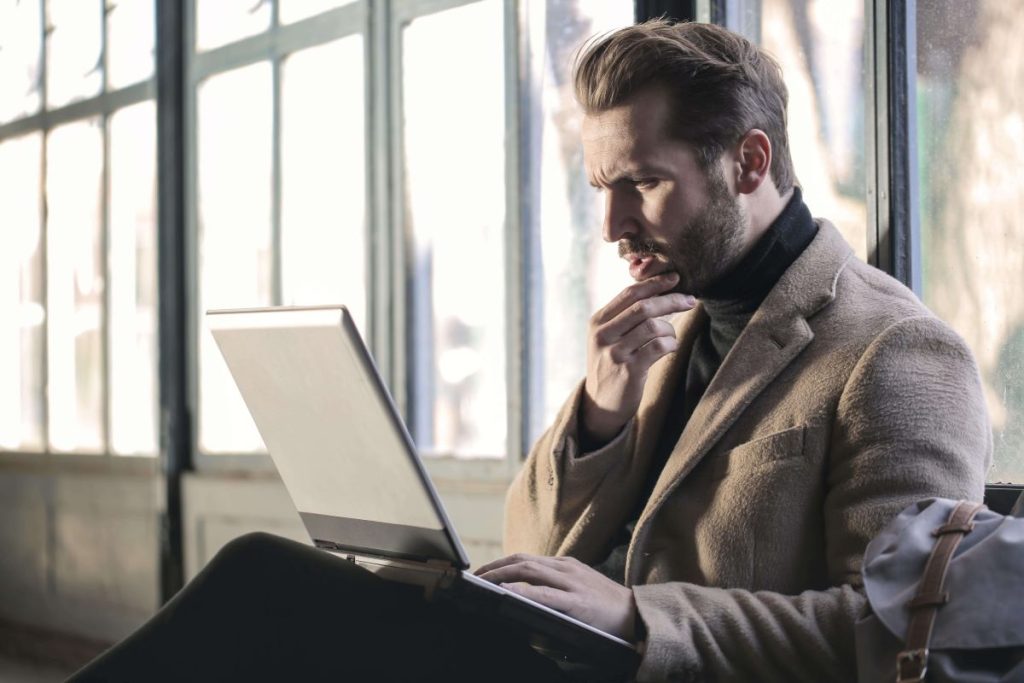 photo of a man deep in thought why looking at his laptop
