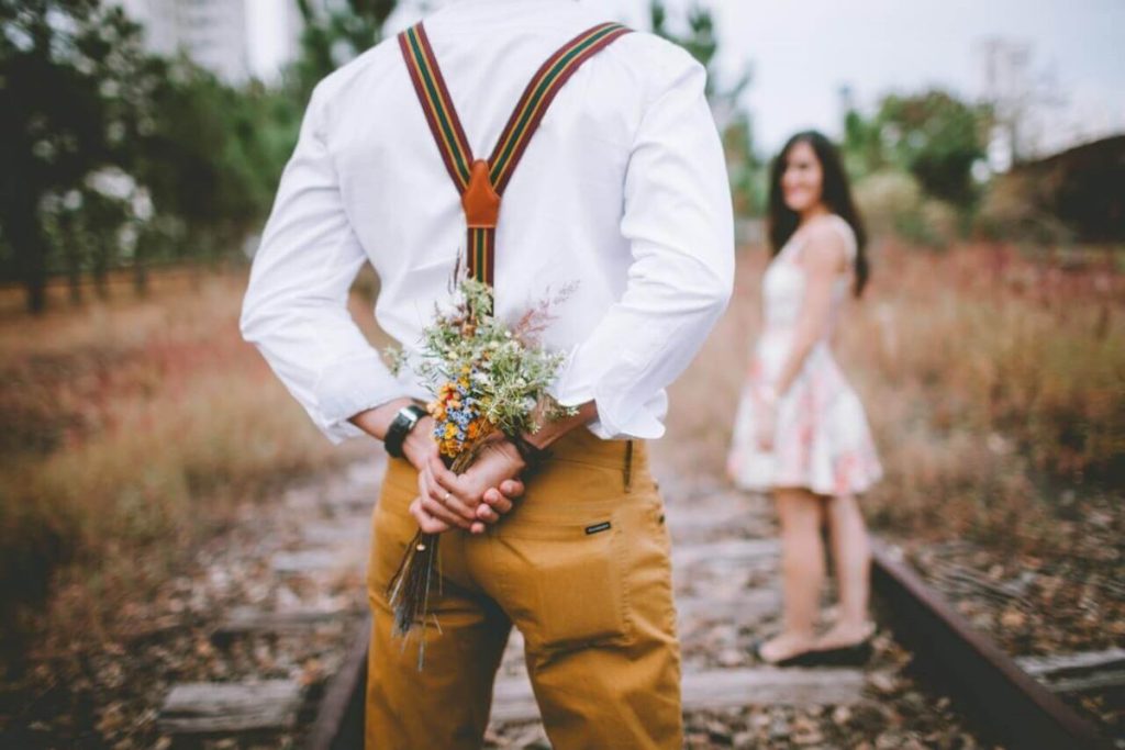 photo of a man holding a bouquet behind his back as a surprise to his partner