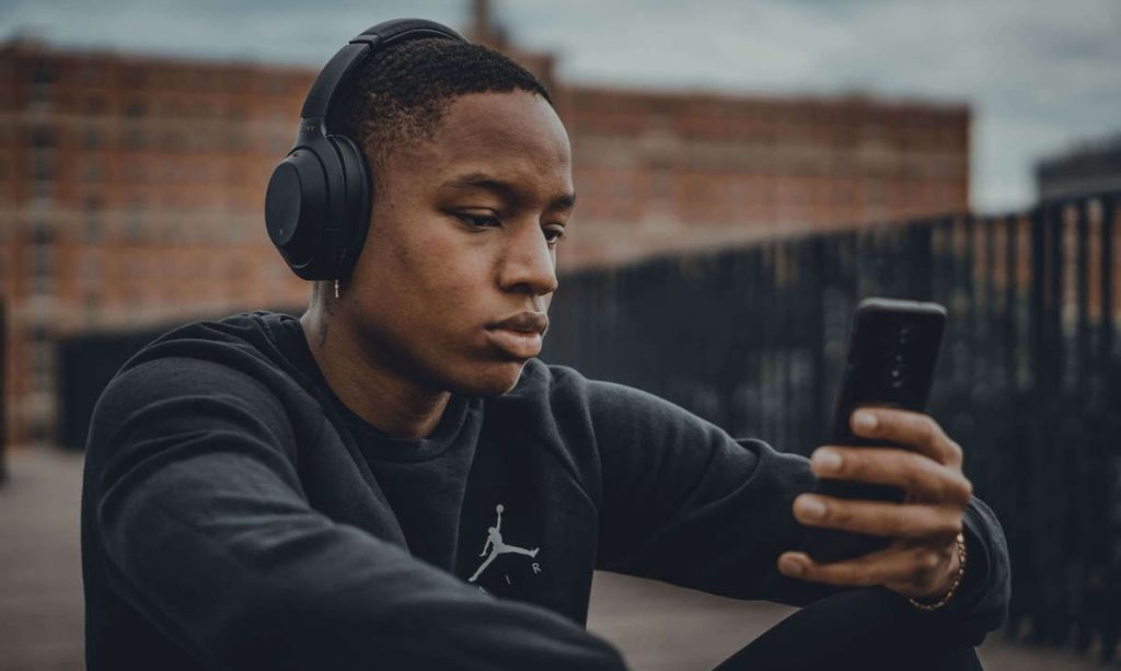 photo of a man listening to music in his headphones and phone