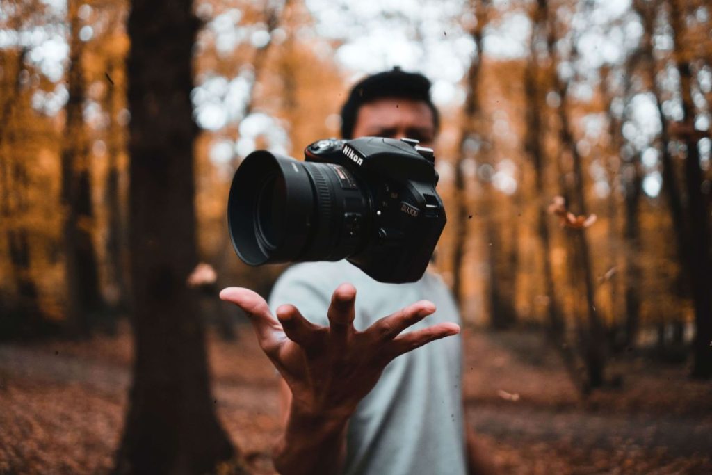 photo of a man tossing the DSLR camera in his hand