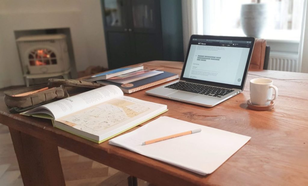 photo of a study desk with a text book, notebook and laptop