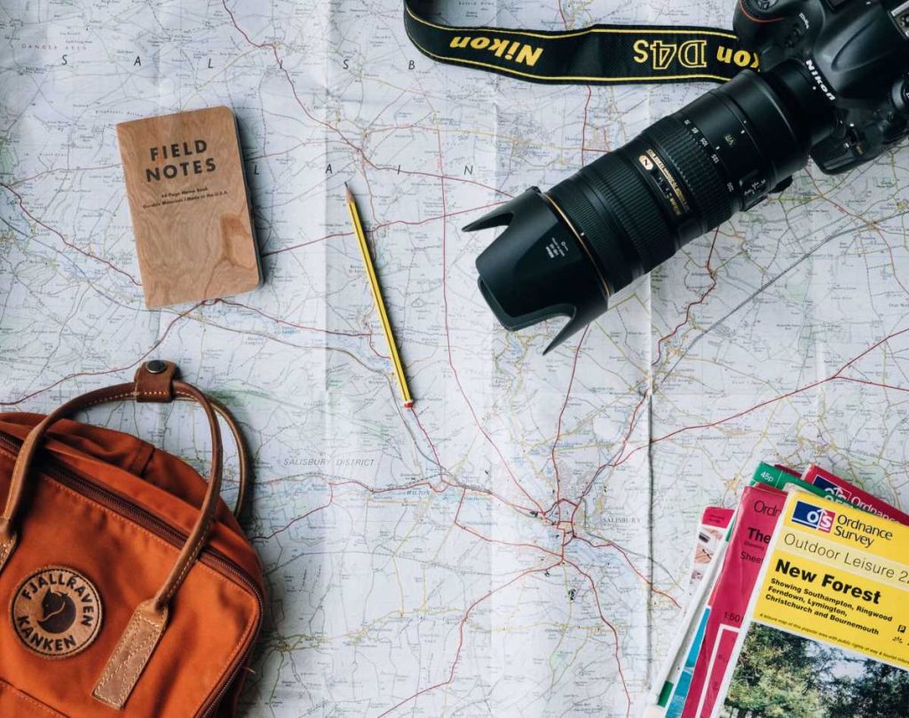 photo of a travel kit complete with a camera, bag, map, and tourist guides