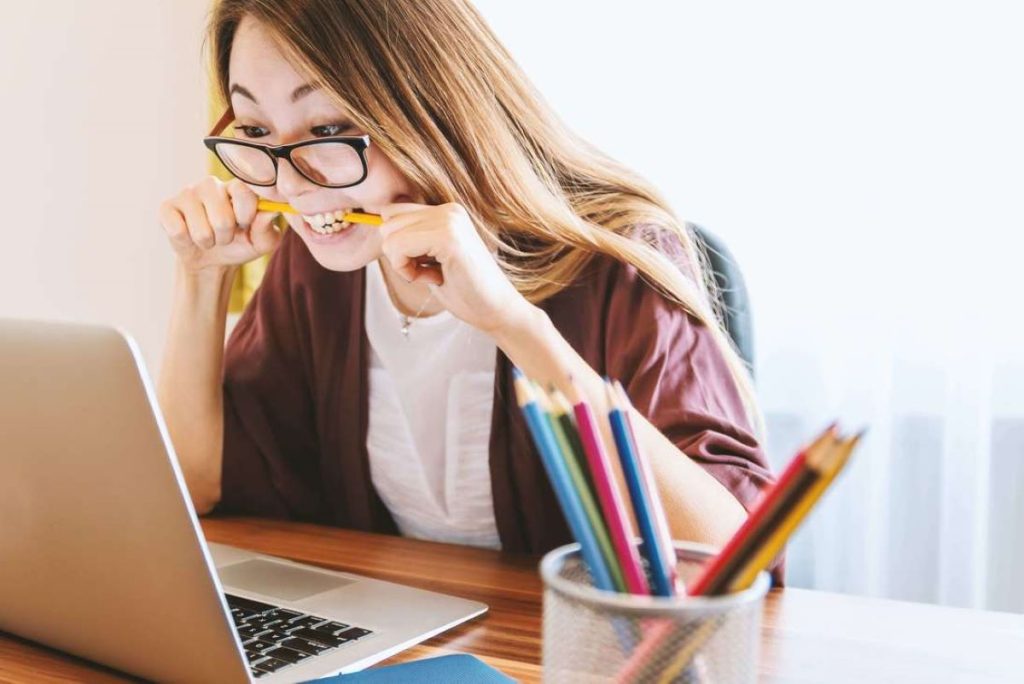 photo of a woman biting a pencil while working