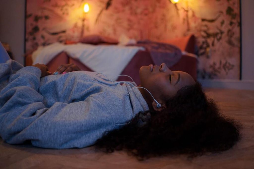 photo of a woman lying on the floor while listening to music with her earbuds