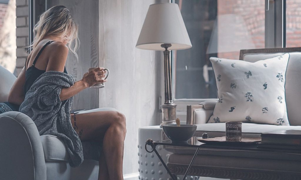 photo of a woman sitting on her couch while drinking tea