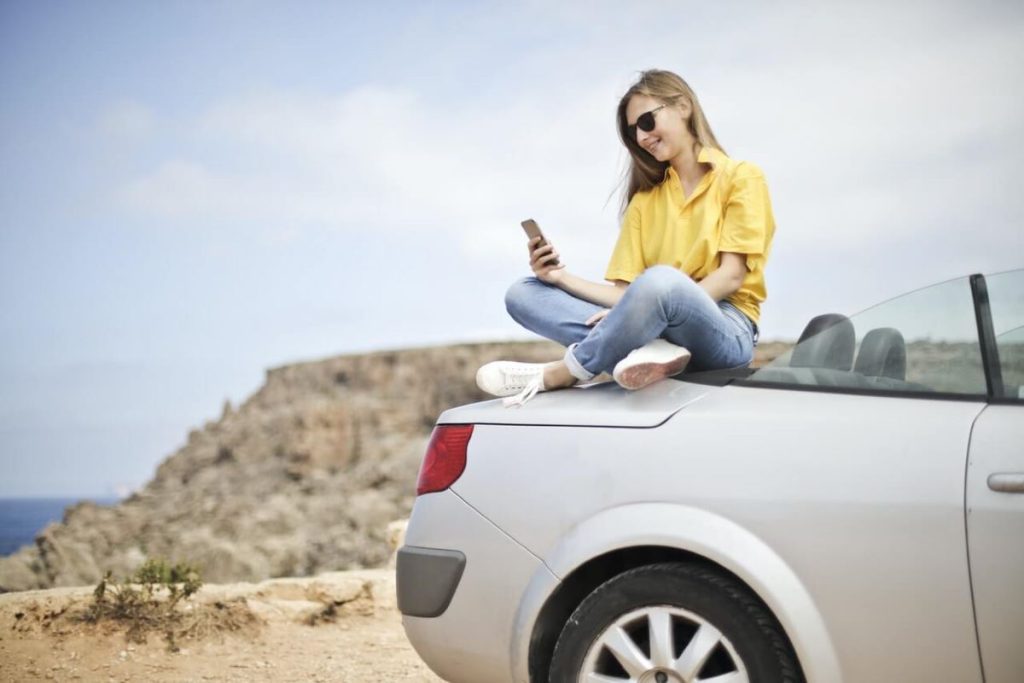 photo of a woman sitting on the trunk of her car