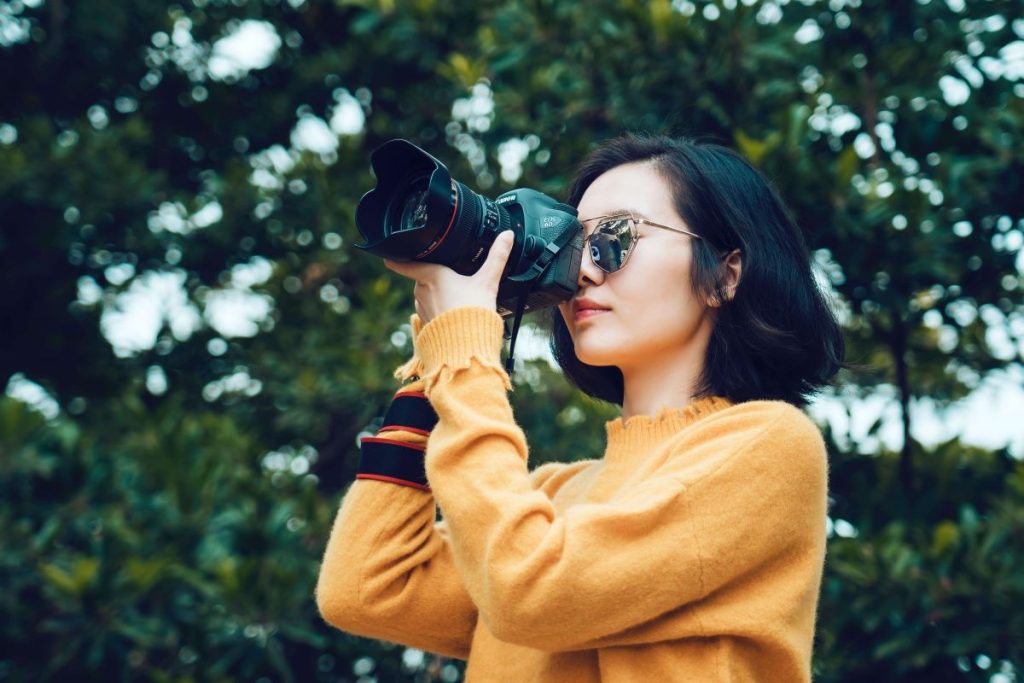 photo of a woman using a dslr camerca
