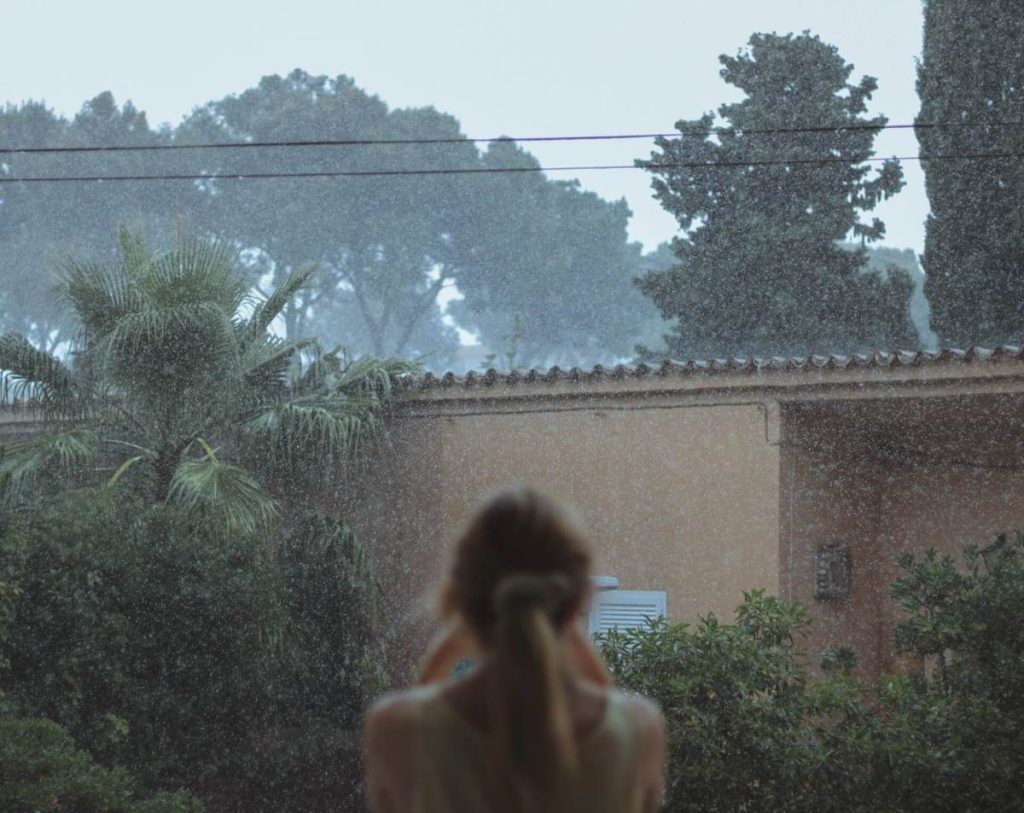 photo of a woman watching the rain
