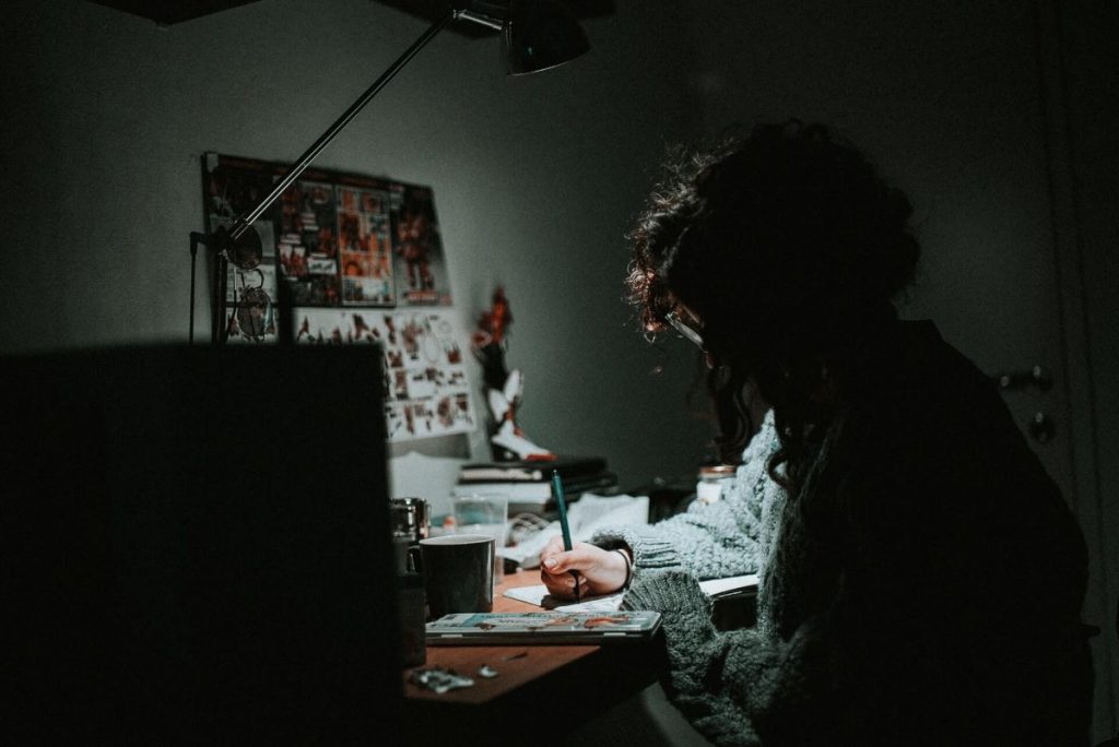 photo of a woman working on a desk with a lamp