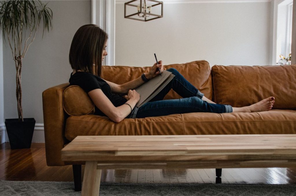 photo of a woman working on her laptop while on the couch