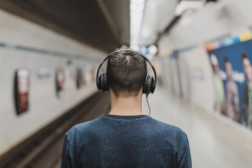 photo of a young man listing to his headset while in the train station