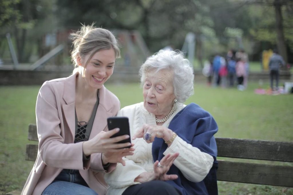 photo of a young woman teaching an elderly woman how to use a phone
