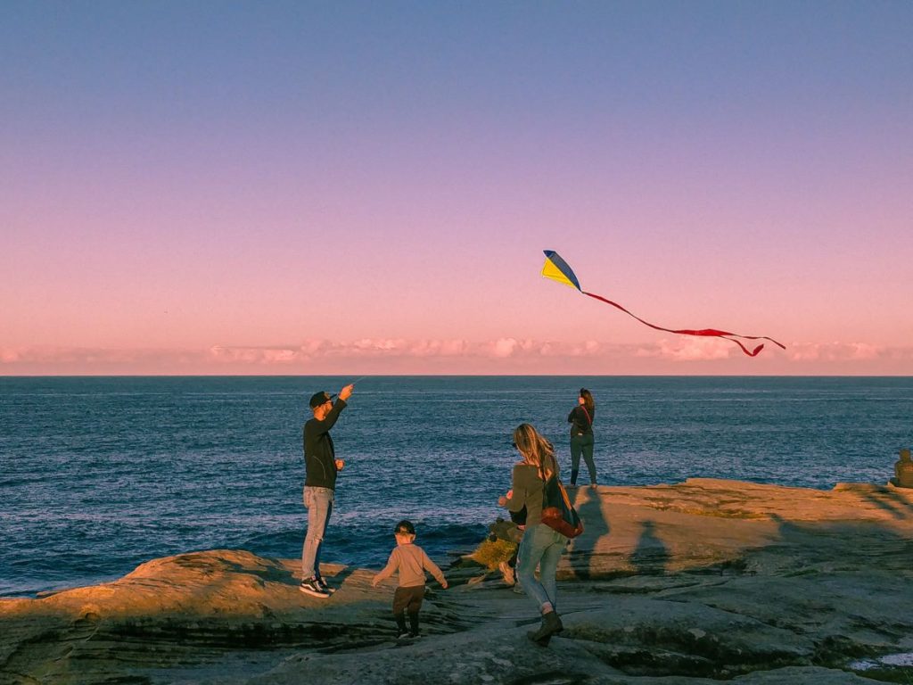 photo of people flying a kite by the ocean