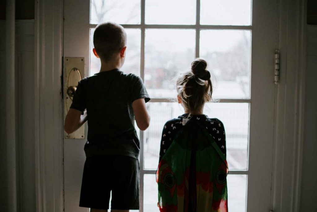 photo of two children looking out of the door window