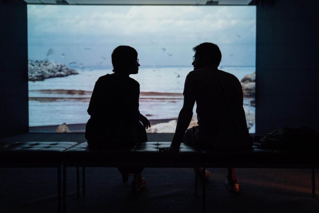 photo of two people relaxing in a cabin with a view of the ocean