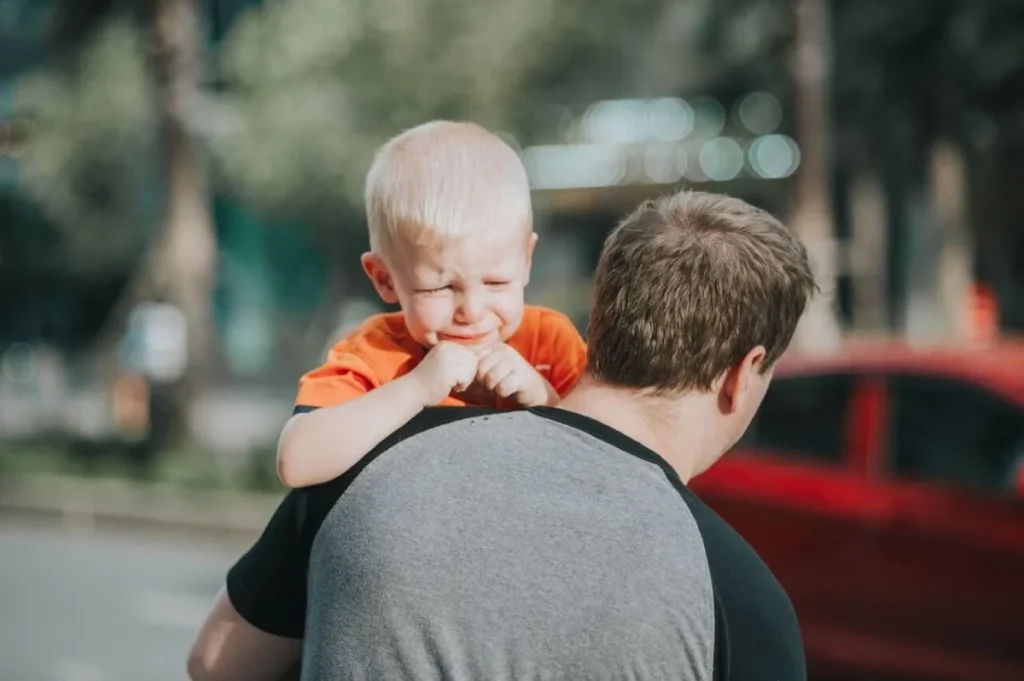 photo of a man carrying his crying child