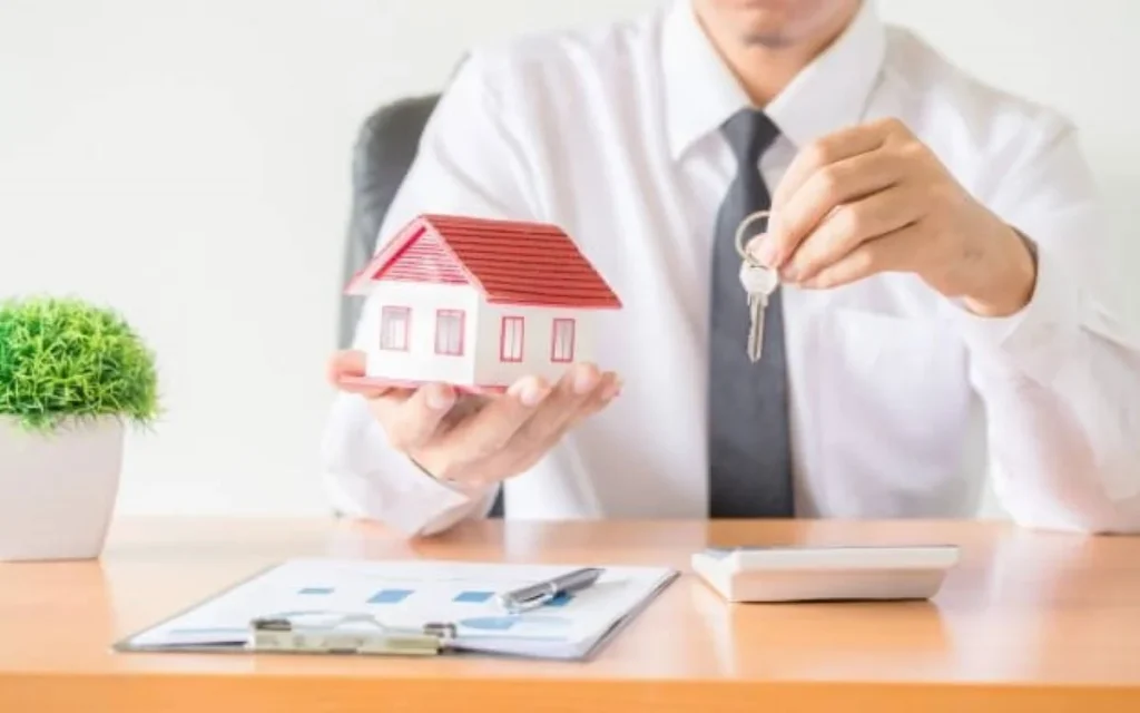 photo of a man holding a house model and keys