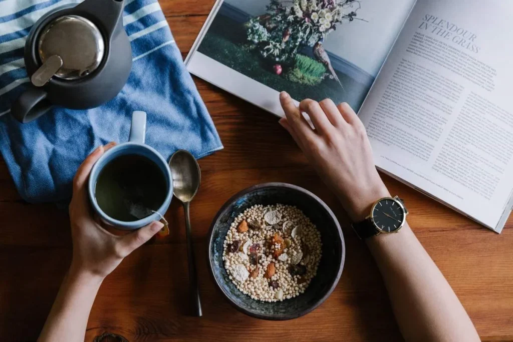 photo of a person with a cup of coffee and a book