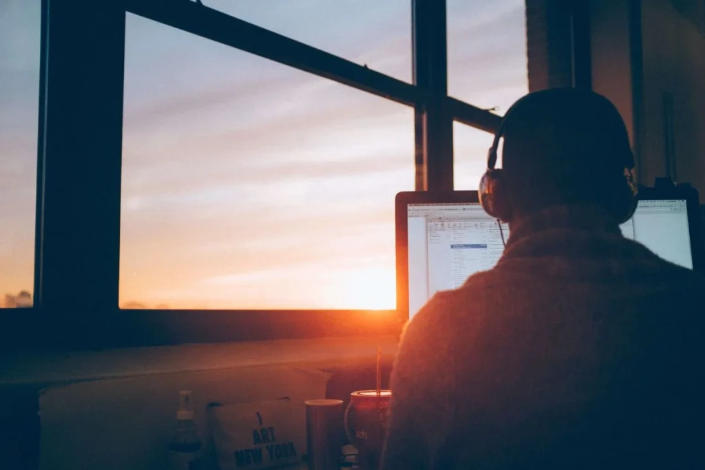 photo of a person working on his laptop while wearing a headset