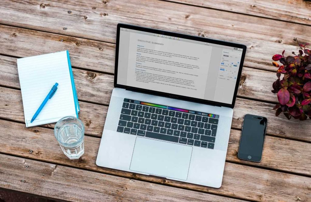 photo of a person working with a laptop and a notebook