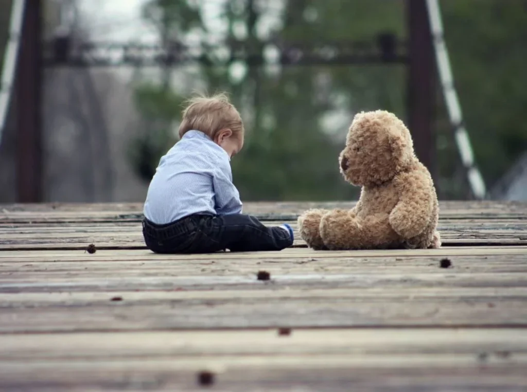 photo of a toddler sitting with their teddy bear