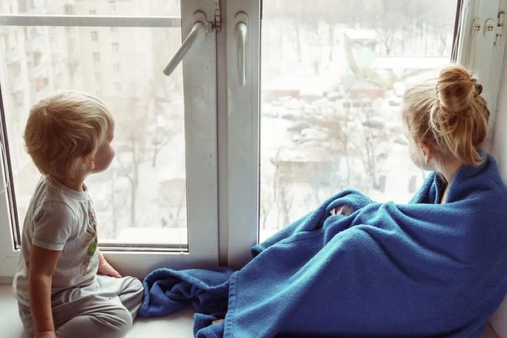 photo of two kids looking out a window